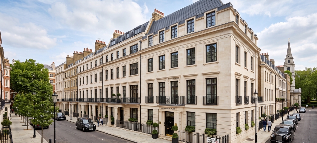 luxury Portland stone townhouses with cast-iron windows and black taxis on Lancelot Place in Knightsbridge, London.